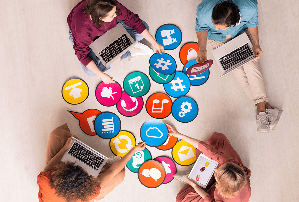 people sitting on the floor with laptops and colorful media icons